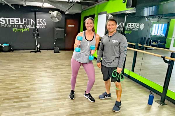 woman holding dumbbells and working with a personal trainer at Steel Fitness Riverport in Bethlehem PA