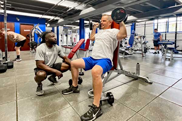 man lifting dumbbells and working with a personal trainer at Steel Fitness Riverport in Bethlehem PA